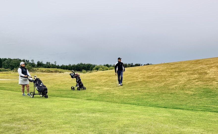 To golfspillere med trillebagger på en gressbane