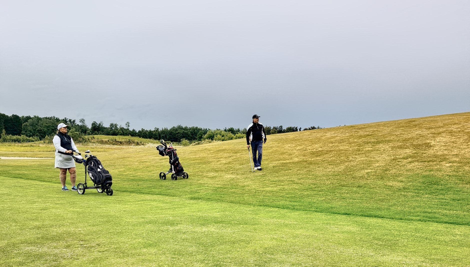 To golfspillere med trillebagger på en gressbane