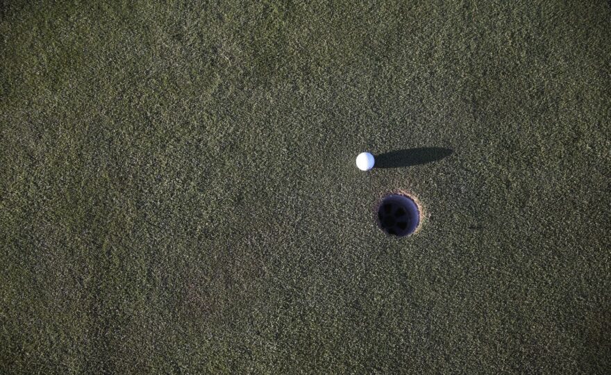 Golfball ligger nær et hull på en kortklipt green