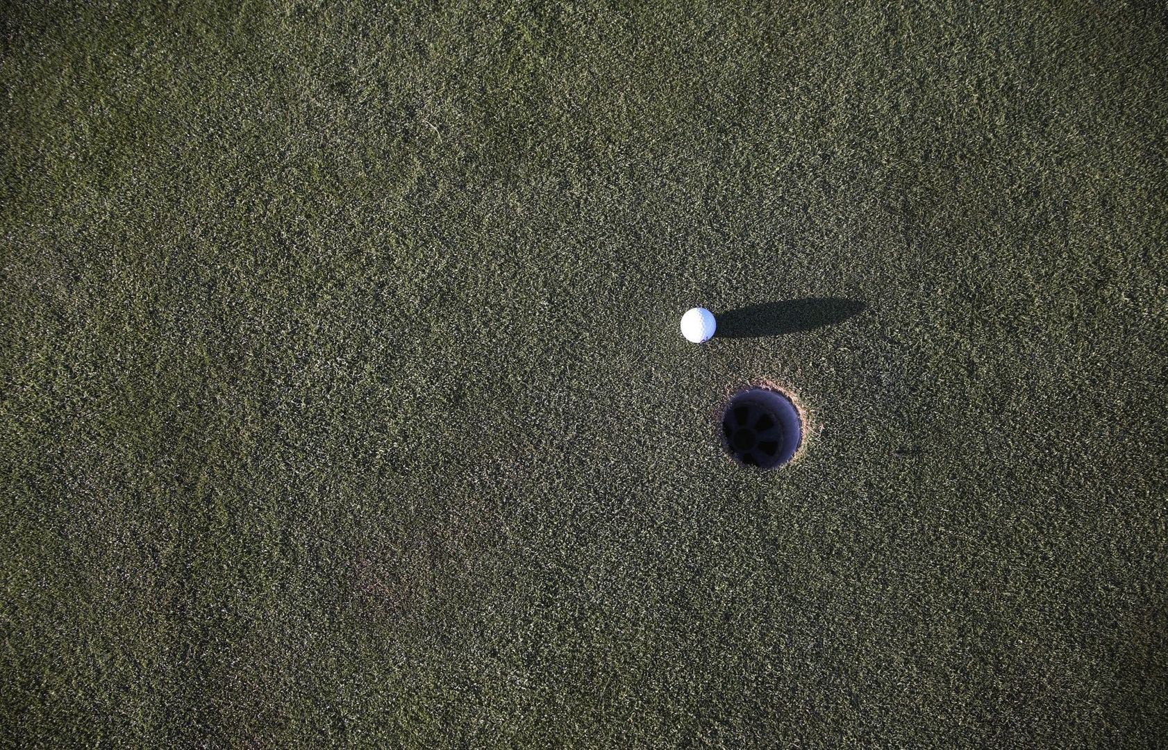 Golfball ligger nær et hull på en kortklipt green